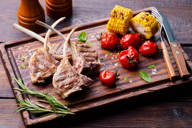 Lamb ribs grilled on cutting board with roasted vegetables. Lamb ribs grilled on cutting board with roasted vegetables rack of lamb stock pictures, royalty-free photos & images