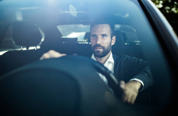 istock Young businessman driving a car while commuting to work. 1129799750