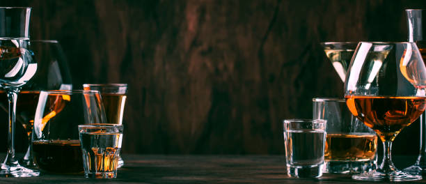 selection of hard strong alcoholic drinks in big glasses and small shot glass in assortent: vodka, cognac, tequila, brandy and whiskey, grappa, liqueur, vermouth, tincture, rum. vintage wooden bar counter background, selective focus, copy space - hard liquor imagens e fotografias de stock