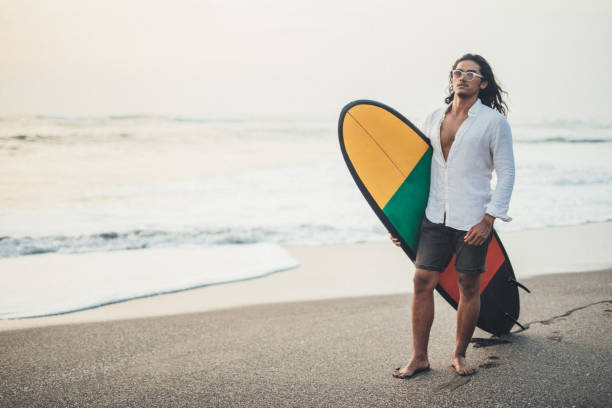 istock Young man carrying surfboard at the beach 1129800476