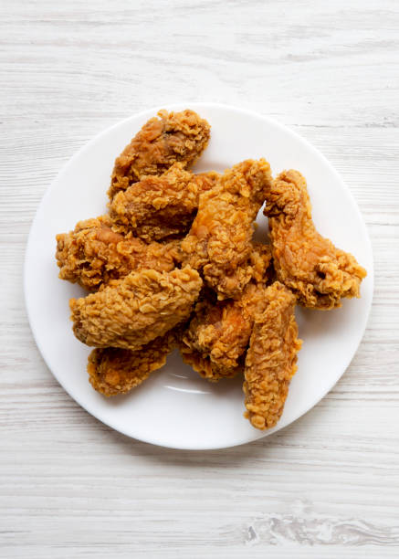 istock Top view, chicken wings on a round white plate over white wooden surface, top view. Flat lay, overhead. 1129801895
