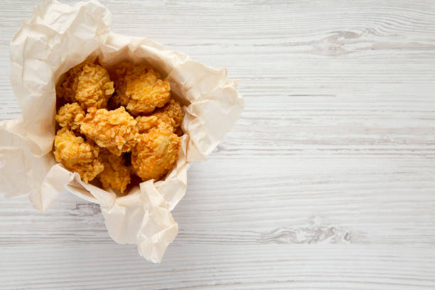 istock Fried chicken bites in paper box over white wooden background, top view. Flat lay, overhead, from above. Copy space. 1129802145