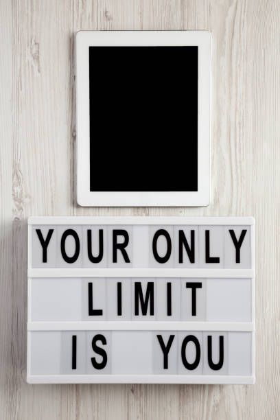 istock 'Your only limit is you' word on lightbox, tablet with blank screen on a white wooden surface, top view. From above, flat lay, overhead. 1129803119