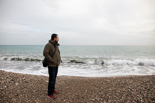 Man walking on the beach on rainy day