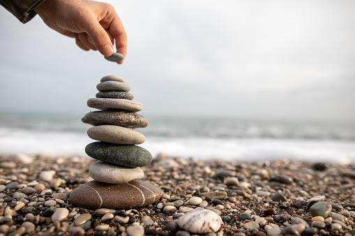 Hand balancing stack of stones on beach