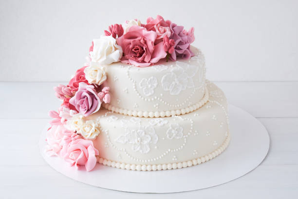 istock Two-tiered white wedding cake decorated with pink flowers 1129807509
