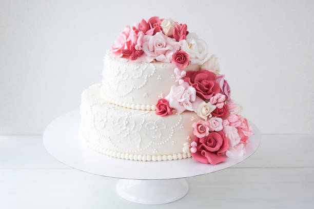 istock Two-tiered white wedding cake decorated with pink flowers 1129807512