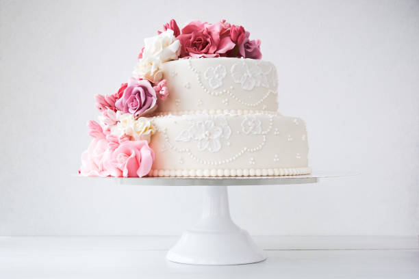 torta nuziale bianca a due livelli decorata con fiori rosa - cake decorations foto e immagini stock
