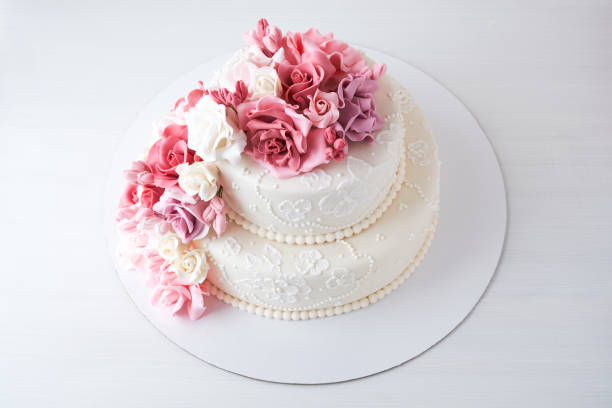 istock Two-tiered white wedding cake decorated with pink flowers 1129807515