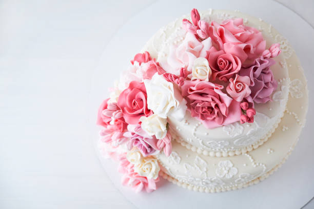 istock Two-tiered white wedding cake decorated with pink flowers 1129807546