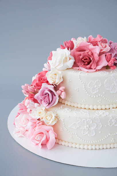 istock Two-tiered white wedding cake decorated with pink flowers 1129807574