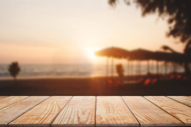 empty wooden table with blurred beach and sunset background stock photo
