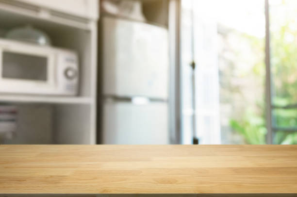 empty wooden table in front of blurred home kitchen background stock photo