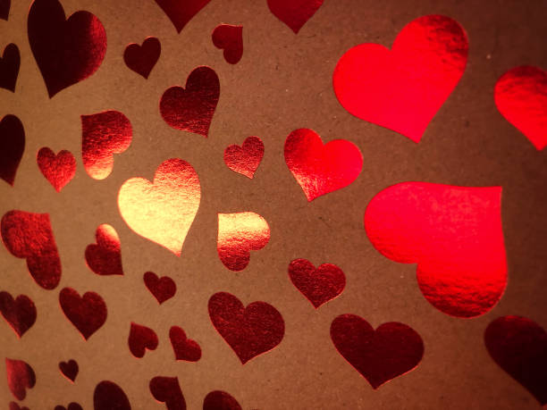 istock Paper surface with metallic red hearts in sunlight 1129807928