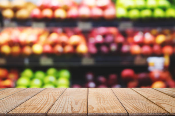 istock empty wooden table top with blurred with bokeh light of shopping mal fruit shelf background, used for display or montage your product 1129810763