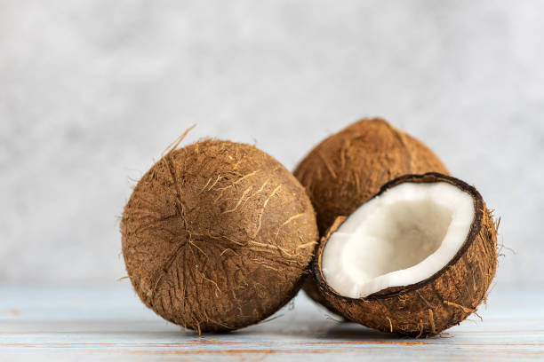 istock Coconut. Whole and half on light wooden background. Side view. 1129810808