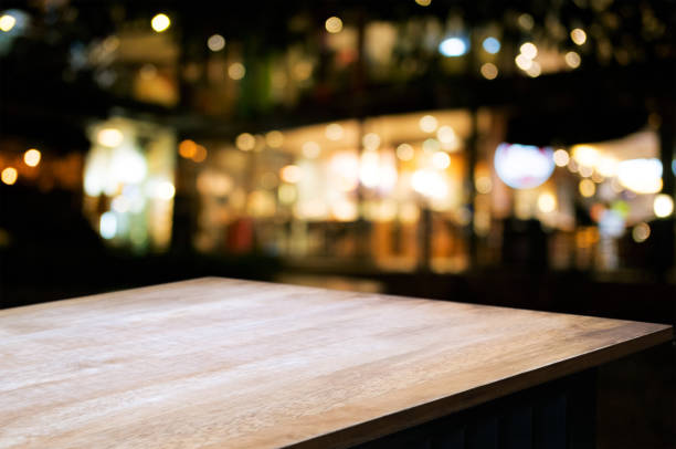 empty wood table in front of blurred montage night market bokeh background stock photo