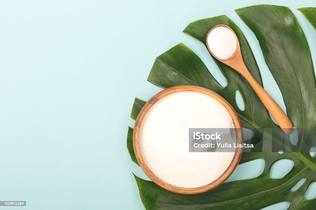 Spoon of powder collagen Collagen powder in bowl and measure spoon on palm leaf background. Extra protein intake. Natural beauty and health supplement. Minimal concept. Plant based collagen concept. Flatlay, top view. Copy space. Collagen Stock Photo