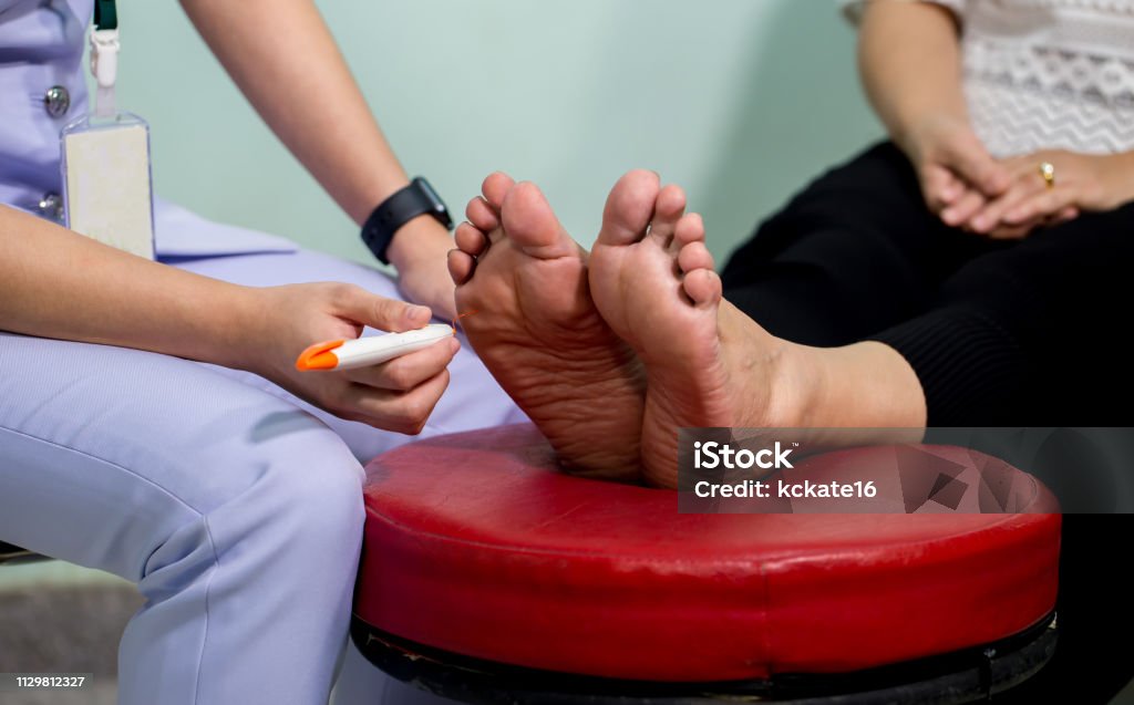 The doctor examines the nerve response with monofilament odiatrist treating feet during procedure. The doctor examines the nerve response with monofilament odiatrist treating feet during procedure. Doctor neurologist examining female patient . Diabetes Stock Photo