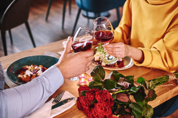 Happy moments. Close-up of couple holding red wine in restaurant stock photo