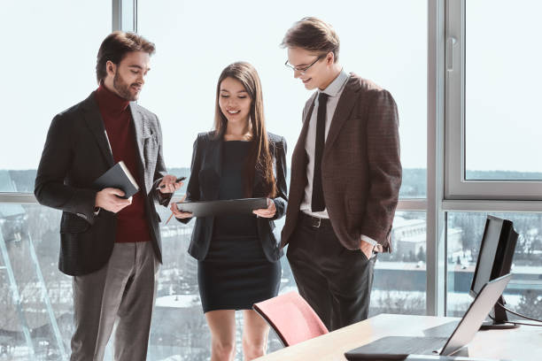 istock Businesspeople at office working together standing looking at pr 1129812490