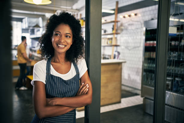 Realizing a dream Cropped shot of an attractive young woman standing in the doorway to her coffee shop with her arms folded franchising photos stock pictures, royalty-free photos & images
