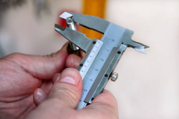 istock Worker with tools in hands. Mechanic is checking and measuring screw size with stainless steel caliper in automechanics workshop, car garage. Hands of mechanic holding steel screw using steel caliper. 1129813576