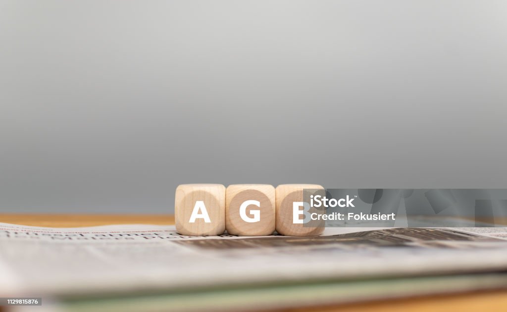 Würfel bilden den deutschen Ausdruck AGB ("Allgemeine Geschäftsbedingungen" auf Englisch) vor einem grauen Hintergrund auf einer Zeitung. - Lizenzfrei Geschäftsbedingungen Stock-Foto