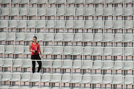 Female spectator standing with water bottle in stadium.