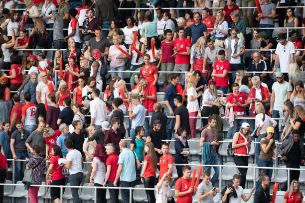 intentionally blurry unrecognizable people and fans with many flags during the event at the open-air stadium