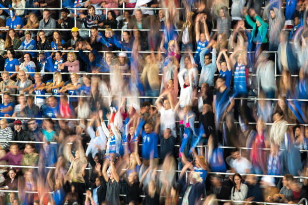 Group of spectators cheering in stadium Blurred motion of group of football fans cheering while watching match in stadium. doing the wave stock pictures, royalty-free photos & images