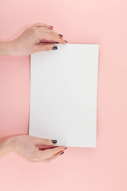 istock Woman hands with blank A4 paper sheet mockup 1129816263