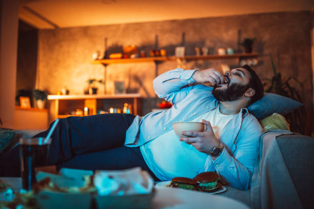 istock Fat man eating fast food 1129817996