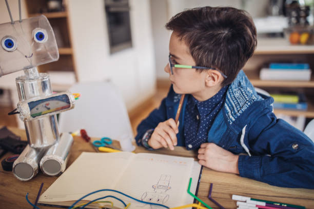 istock Boy making robot toy of recycling material 1129819560