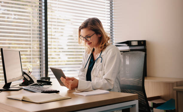 female doctor working on her tablet pc - medico consultorio imagens e fotografias de stock