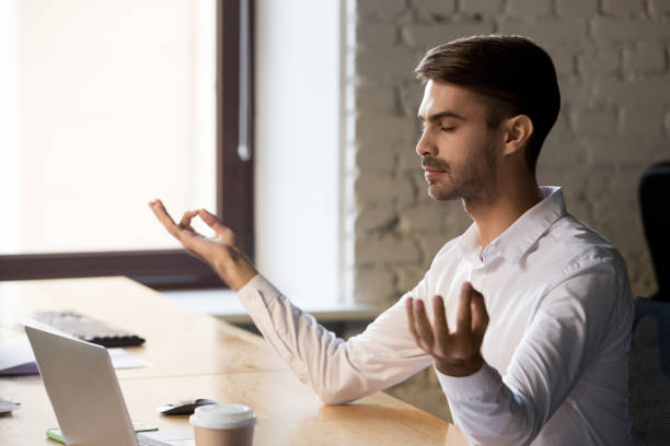 istock Peaceful worker meditating with eyes closed at office table 1129819888
