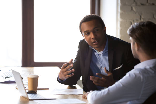 istock Diverse employees negotiate gesturing near laptop in office 1129819915
