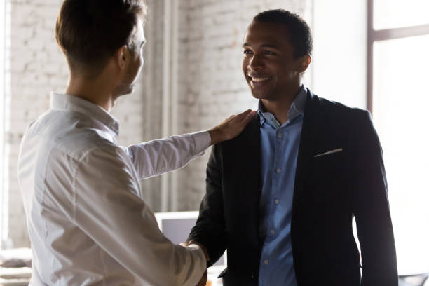 istock Caucasian boss handshake black employee greeting with success 1129819938