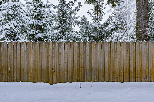 Wooden fence by the village house at winter time.