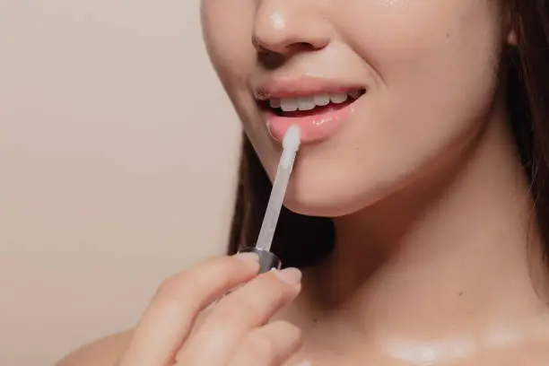 Photo of Applying transparent lip gloss