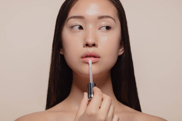 Woman applying transparent lip gloss