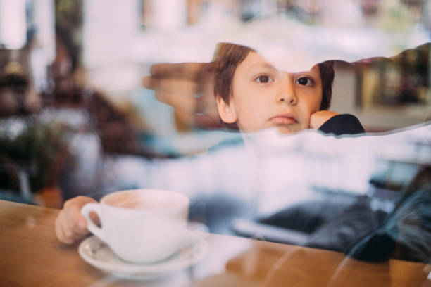 istock Little boy drinking hot chocolate at coffee shop 1129821869