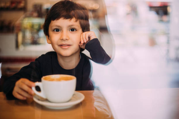 istock Little boy drinking hot chocolate at coffee shop 1129821882