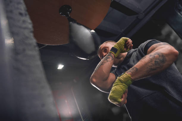 istock Let's get ready to rumble. Arm workout, professional young boxer with green hands wraps hitting punching speed bag in boxing gym 1129821886