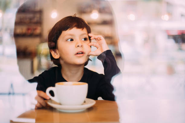istock Little boy drinking hot chocolate at coffee shop 1129822036