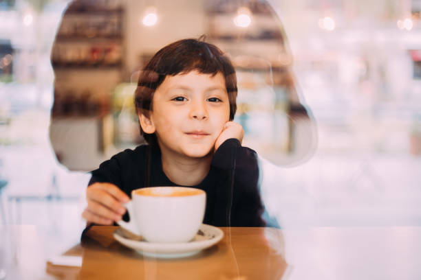 istock Little boy drinking hot chocolate at coffee shop 1129822110