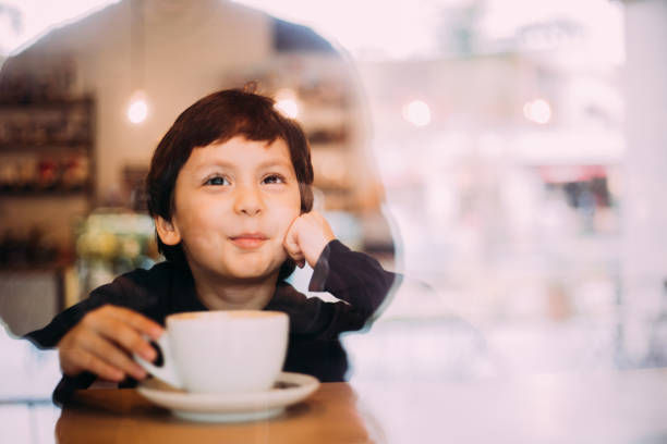 istock Little boy drinking hot chocolate at coffee shop 1129822118