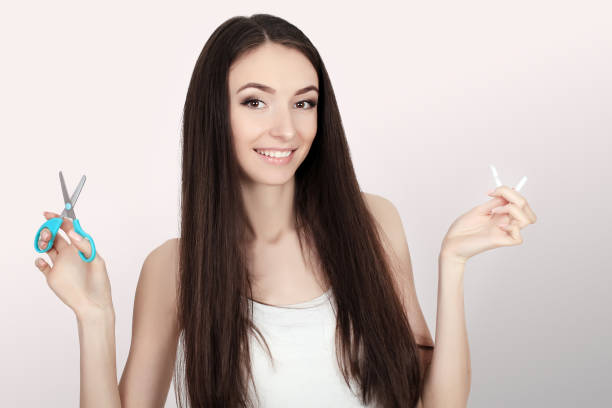 istock Stop smoking concept. Young woman cut cigarettes with scissors happy smiling. focus on hand, scissors and cigarettes 1129823331