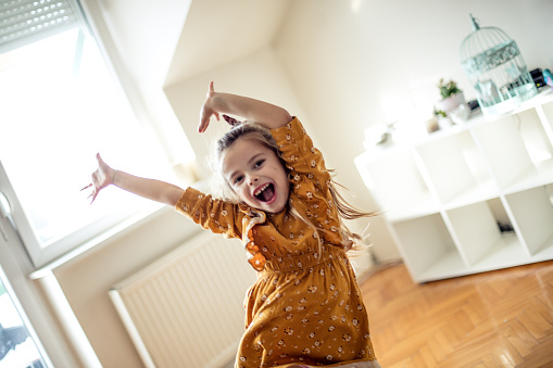 Let's fun. Little girl dancing at home.