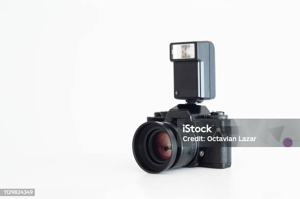 Older Black Film Photo Camera With Flash Unit Attached On Top Isolated Against Pure White Stock Photo - Download Image Now